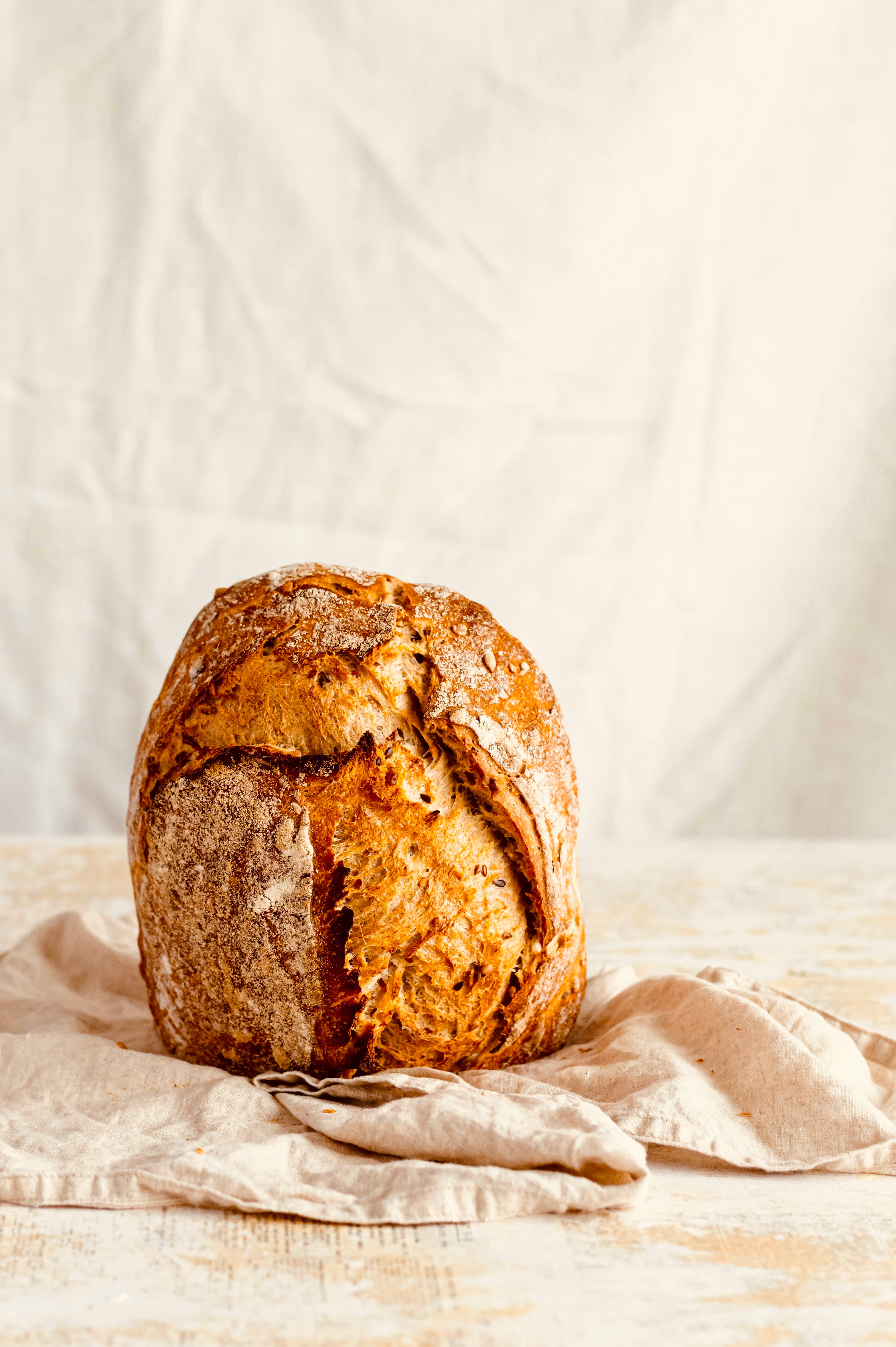 A crusty, golden loaf of homemade bread on a linen cloth