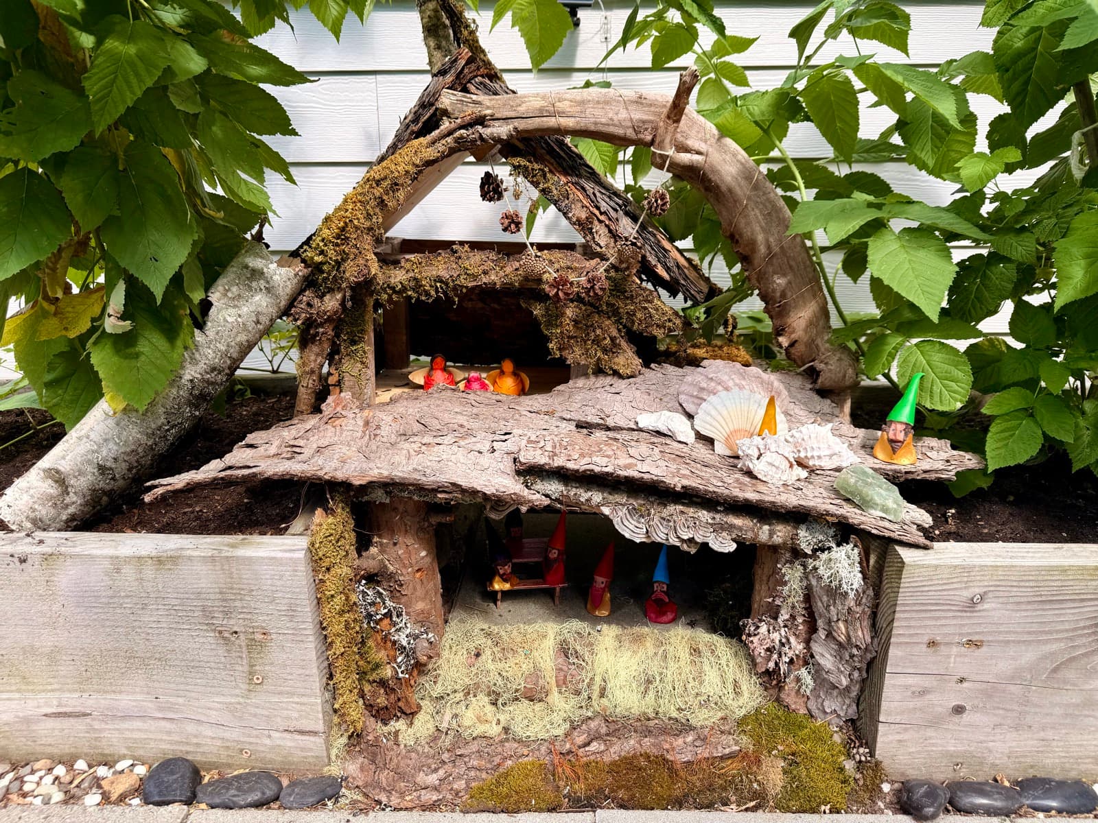 A handmade fairy garden with tiny gnomes tucked among moss and bark