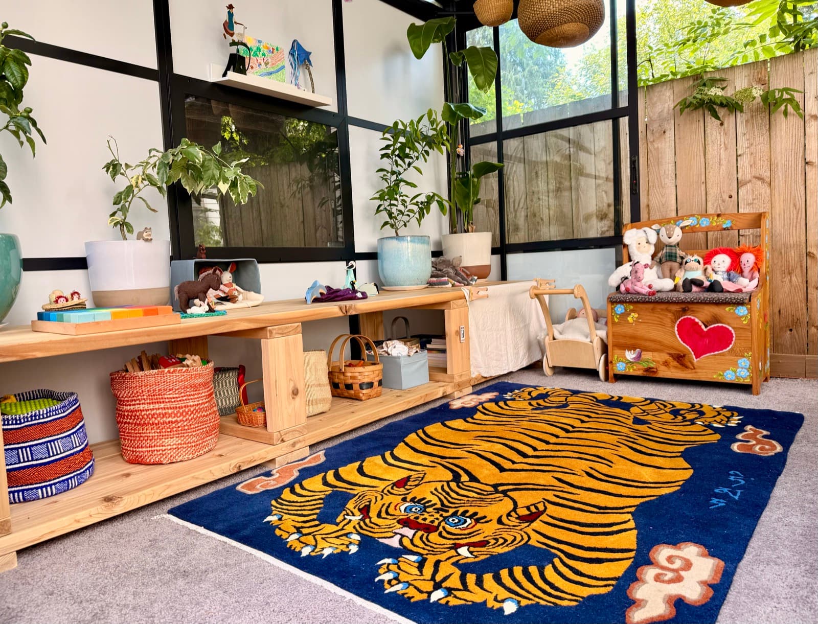 A cozy corner of the studio, with plants, handmade toys, and the tiger rug